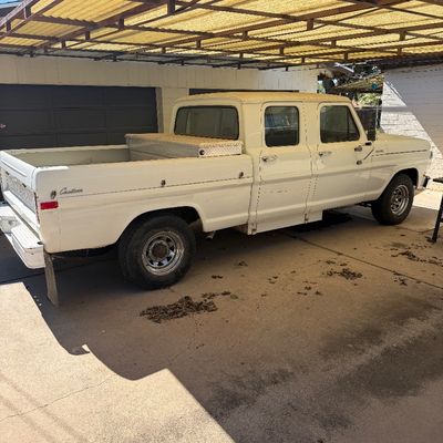 Vintage white Ford F-250 crew cab pickup truck featuring a diamond plate toolbox in the bed, parked under a carport.