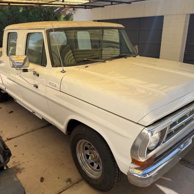 Vintage white Ford F-series crew cab pickup truck parked under a carport, featuring chrome trim and large side mirrors.