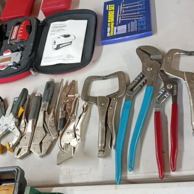 Assortment of hand tools including various locking C-clamp pliers, tongue-and-groove pliers, and a Craftsman laser level kit arranged on...