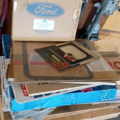 Stack of vintage automotive parts in original packaging, including NOS Ford parts boxes and a Holley performance gasket.