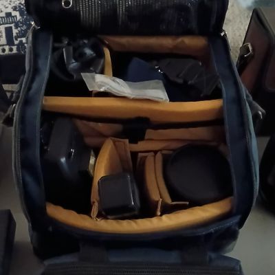 Padded camera gear backpack with padded yellow interior compartments, containing assorted photography accessories.
