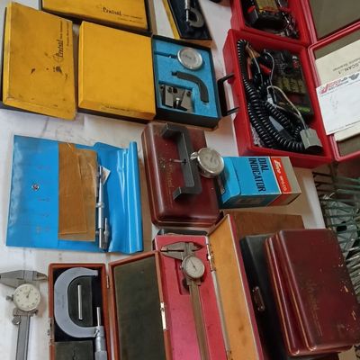Collection of vintage precision measuring tools, including micrometers, dial calipers, and dial indicators in original cases.