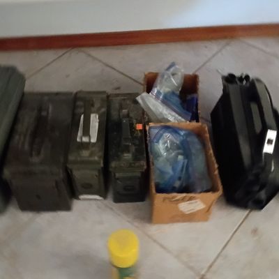Collection of metal and plastic ammunition cans alongside cardboard boxes filled with supplies and hardware.