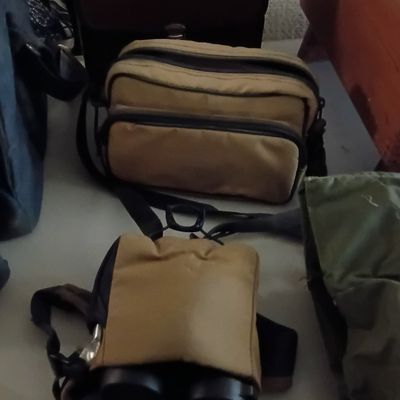 Selection of vintage gear bags and cases, including a dark brown leather camera case and tan nylon utility bags.
