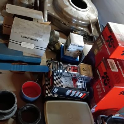 Collection of assorted automotive parts and supplies, including K&N air filters, Stewart-Warner gauge boxes, WIX oil filter, and...