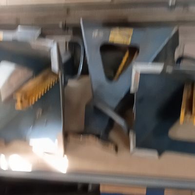 Set of heavy-duty steel automotive jack stands with yellow ratchet bars resting on a workshop shelf.