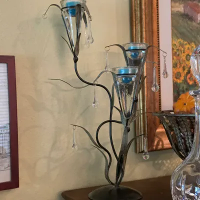 Sale Photo Thumbnail #77: Wrought iron tree-form candelabra featuring conical glass votive cups with dangling crystal prisms, shown alongside a cut glass decanter.