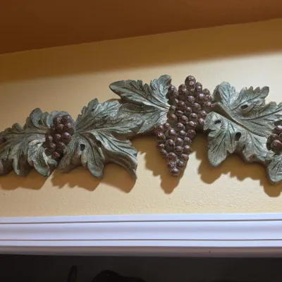 Sale Photo Thumbnail #69: Carved wood wall pediment featuring a detailed grapevine motif with leaves and clusters of grapes in a distressed green and brown finish.