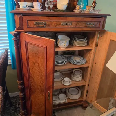 Sale Photo Thumbnail #97: Vintage wood cabinet with burled veneer doors and drawer, filled with various china dish sets and teacups.