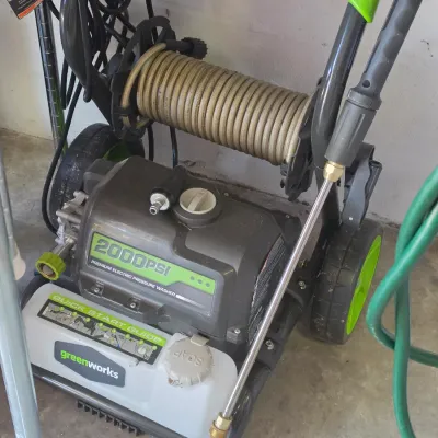 Sale Photo Thumbnail #278: Greenworks 2000 PSI electric pressure washer on a wheeled cart, featuring a built-in hose reel and spray wand.