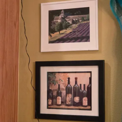 Sale Photo Thumbnail #11: Pair of framed photographic prints depicting a lavender field with abbey and a still life of wine bottles.