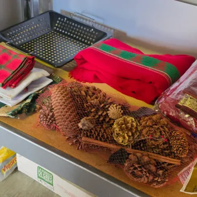 Sale Photo Thumbnail #292: Collection of holiday linens and decor, including red and green textiles, a netted bag of pinecones, and a metal perforated tray tray.