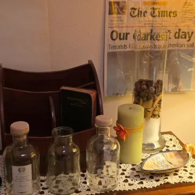 Sale Photo Thumbnail #247: Collection of decorative tabletop items, including glass bottles, a wooden letter organizer, a pillar candle, and framed September 12, 2001 newspaper headline.
