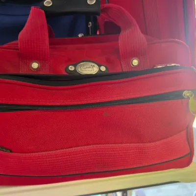 Sale Photo Thumbnail #314: Red Ricardo Beverly Hills canvas carry-on duffel bag featuring dual handles, black zipper trim, and a front zippered pocket.