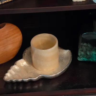 Sale Photo Thumbnail #94: Collection of decorative home accents, including a carved wooden seed pod vase, alabaster cylinder cup, seashell tray, and filled glass bottle.