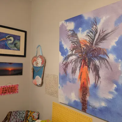 Sale Photo Thumbnail #167: Large wrapped canvas painting featuring a colorful palm tree against a cloudy blue sky, displayed alongside smaller framed wall art.