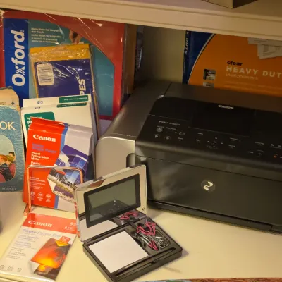 Sale Photo Thumbnail #241: Canon PIXMA printer alongside assorted office supplies, Canon photo paper, a vintage religious book, and a Yankee Candle.