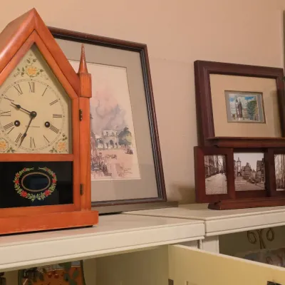 Sale Photo Thumbnail #238: Gothic steeple-style Seth Thomas mantle clock alongside framed artwork, a multi-opening picture frame, and a studio art pottery cylinder vase.
