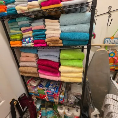 Sale Photo Thumbnail #260: Black wire shelving unit filled with neatly folded, colorful bath and hand towels, paper products, and household supplies.