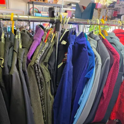 Sale Photo Thumbnail #318: Selection of men's and women's outerwear, sweaters, and tops hanging on a chrome garment rack.
