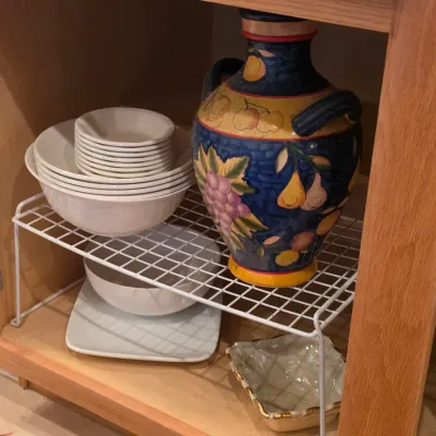 Sale Photo Thumbnail #32: Hand-painted Italian style ceramic urn with fruit motifs alongside stacked white dishware on cabinet organizer shelves.
