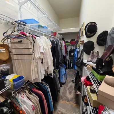 Sale Photo Thumbnail #152: Walk-in closet filled with women's clothing, shoes, hats, and handbags arranged on wire shelving racks.