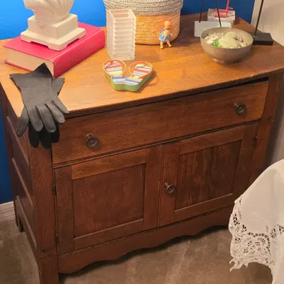 Sale Photo Thumbnail #179: Antique oak washstand cabinet featuring a wide upper drawer over a double-door lower storage compartment, displayed with various home decor items.