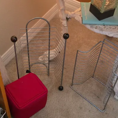 Sale Photo Thumbnail #120: Two metal wire CD rack holders and a red soft-sided CD storage case on a carpeted floor.