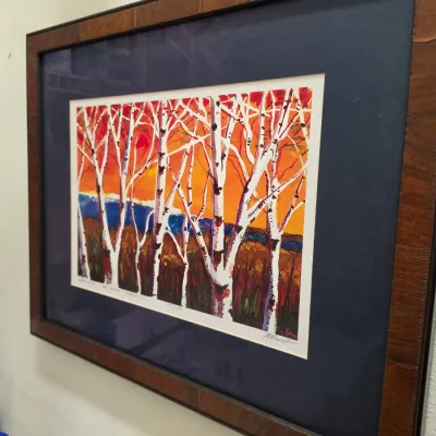 Sale Photo Thumbnail #266: Framed limited edition art print depicting birch trees against a colorful sunset, presented with a dark navy mat and a rustic wooden frame.