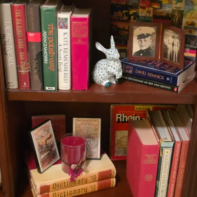 Sale Photo Thumbnail #218: Wooden bookcase filled with hardback books, small framed vintage photos, a porcelain rabbit figurine, and decorative accessories.