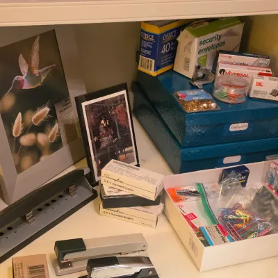 Sale Photo Thumbnail #240: Collection of office supplies including staplers, paper clips, hole punchers, staples, security envelopes, and decorative framed artwork.