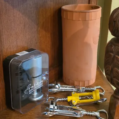 Sale Photo Thumbnail #76: Collection of wine accessories including a terracotta wine cooler, boxed Rabbit wine preserver set, and several winged corkscrews.