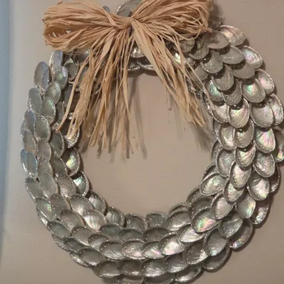 Sale Photo Thumbnail #177: Handcrafted decorative wreath made of iridescent abalone shells, topped with a raffia ribbon bow.