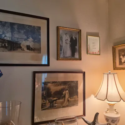 Sale Photo Thumbnail #131: Collection of framed antique black-and-white portraits and landscape art prints displayed on a wall above a table lamp.