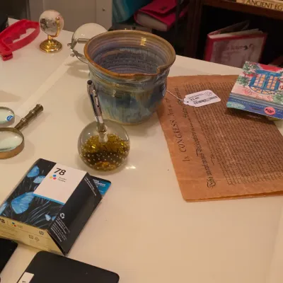 Sale Photo Thumbnail #243: Collection of desk accessories and stationery, including a ceramic vessel, magnifying glasses, a pen holder, an HP ink cartridge, and decorative paper goods.