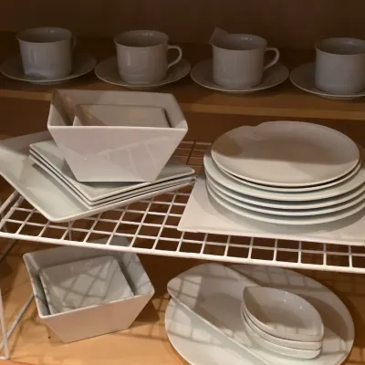 Sale Photo Thumbnail #33: Set of modern white ceramic dinnerware, including square plates, bowls, teacups with saucers, and serving dishes, organized in a cabinet.