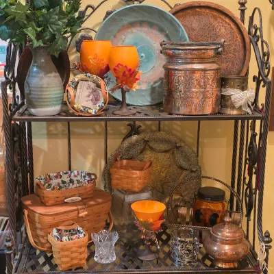 Sale Photo Thumbnail #58: Black wrought iron bakers rack displayed with Longaberger woven baskets, copper vessels, studio pottery plates, and fall-themed stemware.