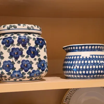 Sale Photo Thumbnail #39: Two pieces of Polish pottery, including a square lidded jar with a blue floral pattern and a small creamer pitcher with a blue geometric design.