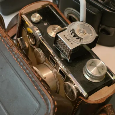Sale Photo Thumbnail #209: Vintage Argus C3 35mm rangefinder camera equipped with an Argus light meter accessory, housed in a original brown leather ever-ready case.
