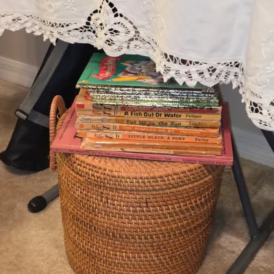 Sale Photo Thumbnail #175: Stack of vintage children's hardbound books including Beginner Books titles resting atop a round woven wicker basket.