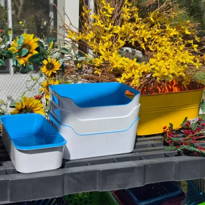 Sale Photo Thumbnail #332: Collection of home organization bins and floral decor, including plastic white-and-blue stacking totes, a yellow metal tub planter, and decorative wreaths.