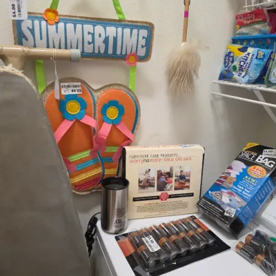 Sale Photo Thumbnail #264: Assortment of household supplies, including an ironing board, Space Bags, furniture care kit, batteries, liquid soap, and summer wall decor.