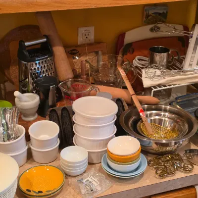 Sale Photo Thumbnail #16: Assortment of kitchenware including Pyrex measuring cups, ramekins, stainless steel mixing bowls, a white handheld mixer, wooden rolling pins, and various cooking utensils.