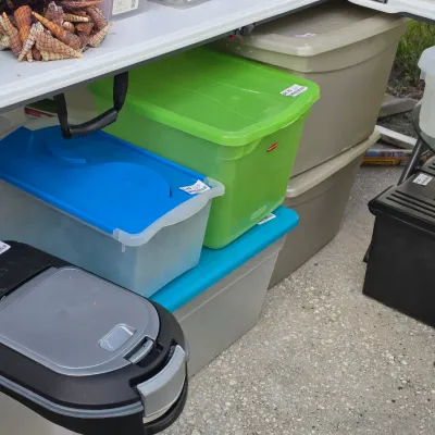 Sale Photo Thumbnail #333: Assortment of plastic storage totes and containers, including a lime green Rubbermaid tote, clear storage bins with blue lids, and a pet food container.