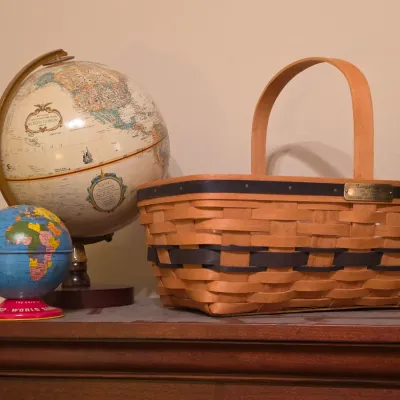 Sale Photo Thumbnail #215: Vintage Longaberger woven basket with brass logo plate displayed alongside a Replogle desk globe and a vintage tin toy globe.