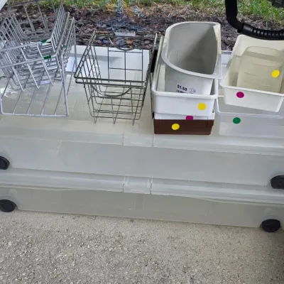 Sale Photo Thumbnail #323: Selection of household storage items including stacked under-bed plastic rolling bins, wire baskets, and small plastic organizer trays.