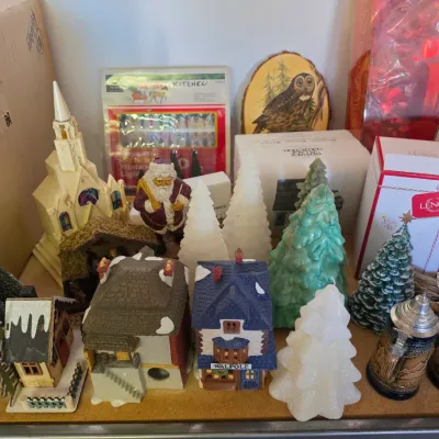 Sale Photo Thumbnail #289: Collection of Christmas decor including miniature village houses, white and green tree candles, bottle brush trees, a Santa figurine, and Lenox boxed items.