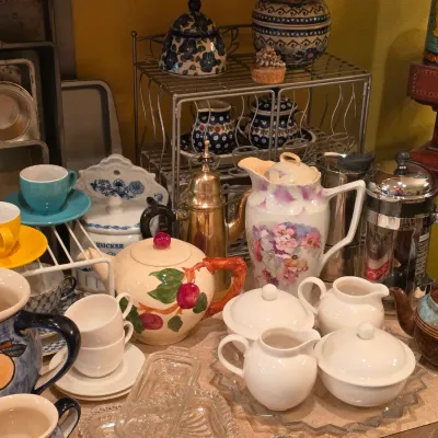 Sale Photo Thumbnail #26: Collection of assorted kitchenware and teacups, featuring a hand-painted floral pitcher, Polish pottery pieces, colorful espresso sets, and a French press.