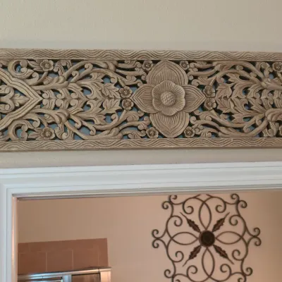 Sale Photo Thumbnail #140: Intricately carved Balinese-style wood wall panel with floral design mounted above a doorway.