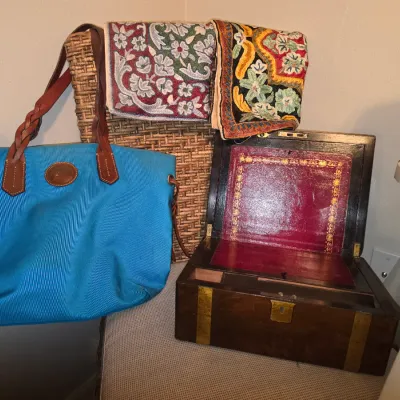Sale Photo Thumbnail #170: Bright blue Dooney & Bourke canvas tote with braided leather handles, displayed alongside an antique wooden lap desk featuring brass fittings and a burgundy leather writing surface, and two embroidered textiles.